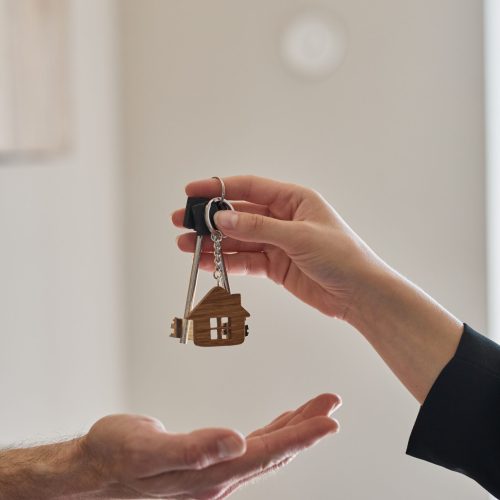 Vertical close up of female real estate agent giving keys to client buying new house, copy space